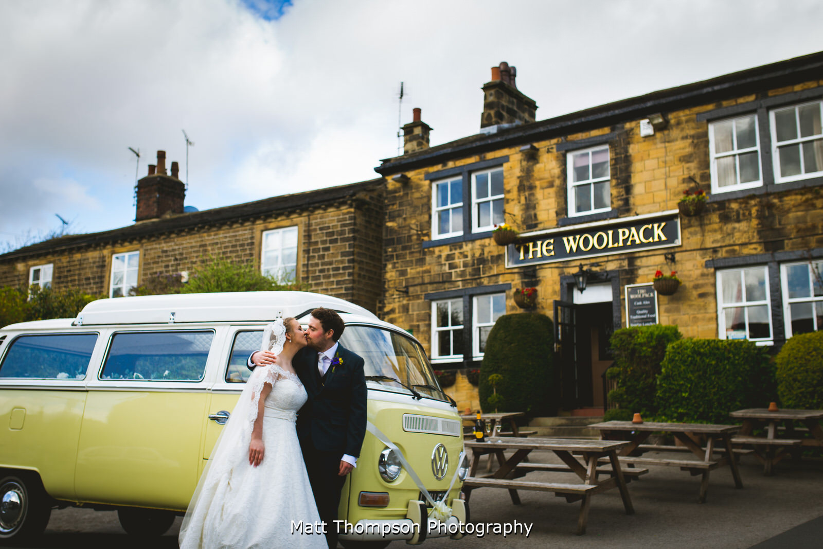 bride and groom kissing in front of the wooldpack with their campervan wedding car