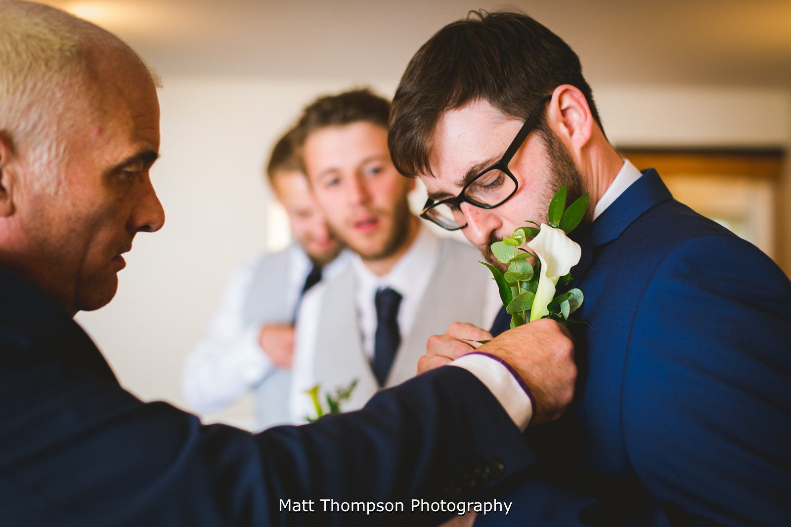 father of the groom putting on button hole