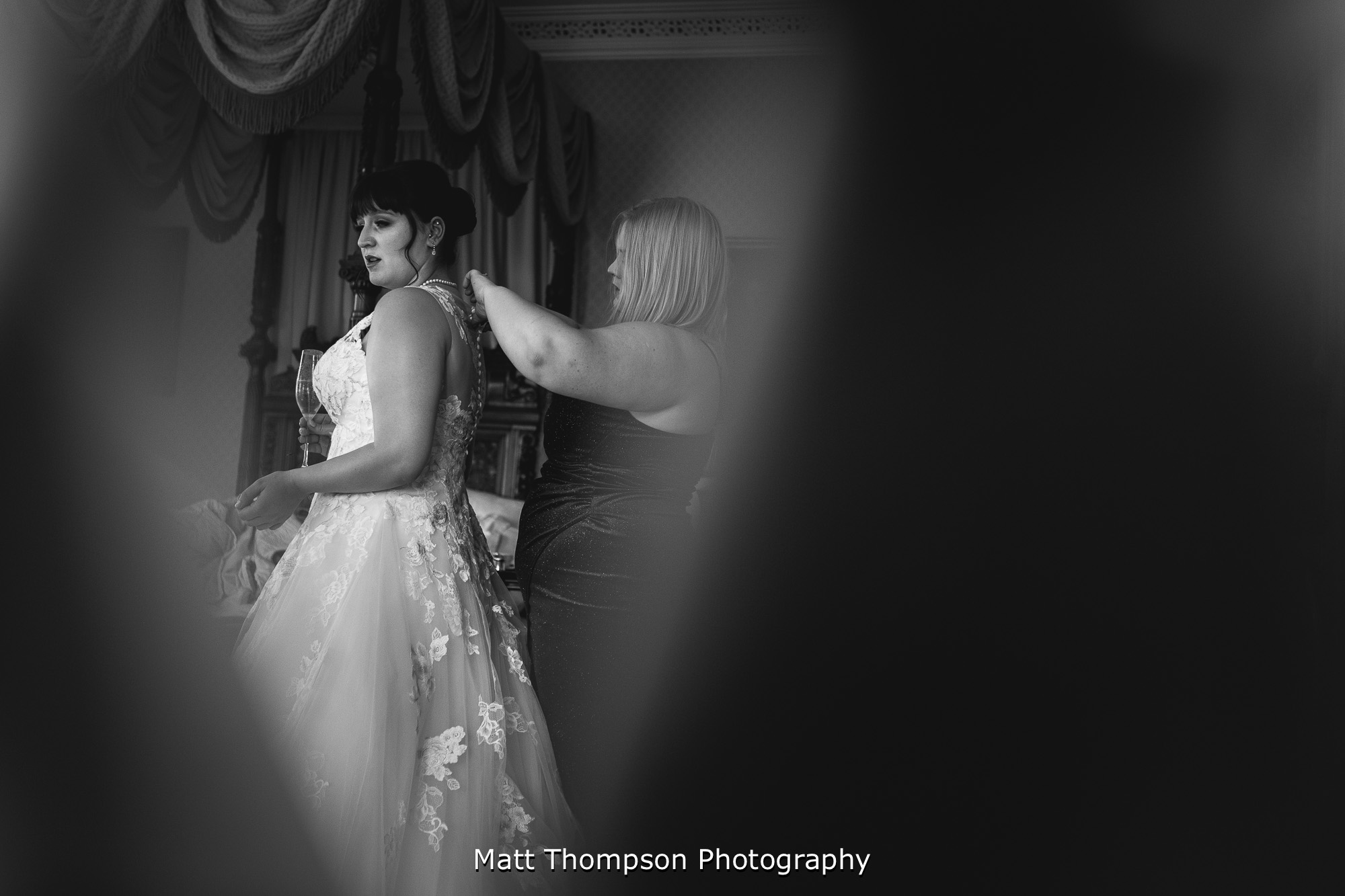 bridesmaid doing up wedding dress